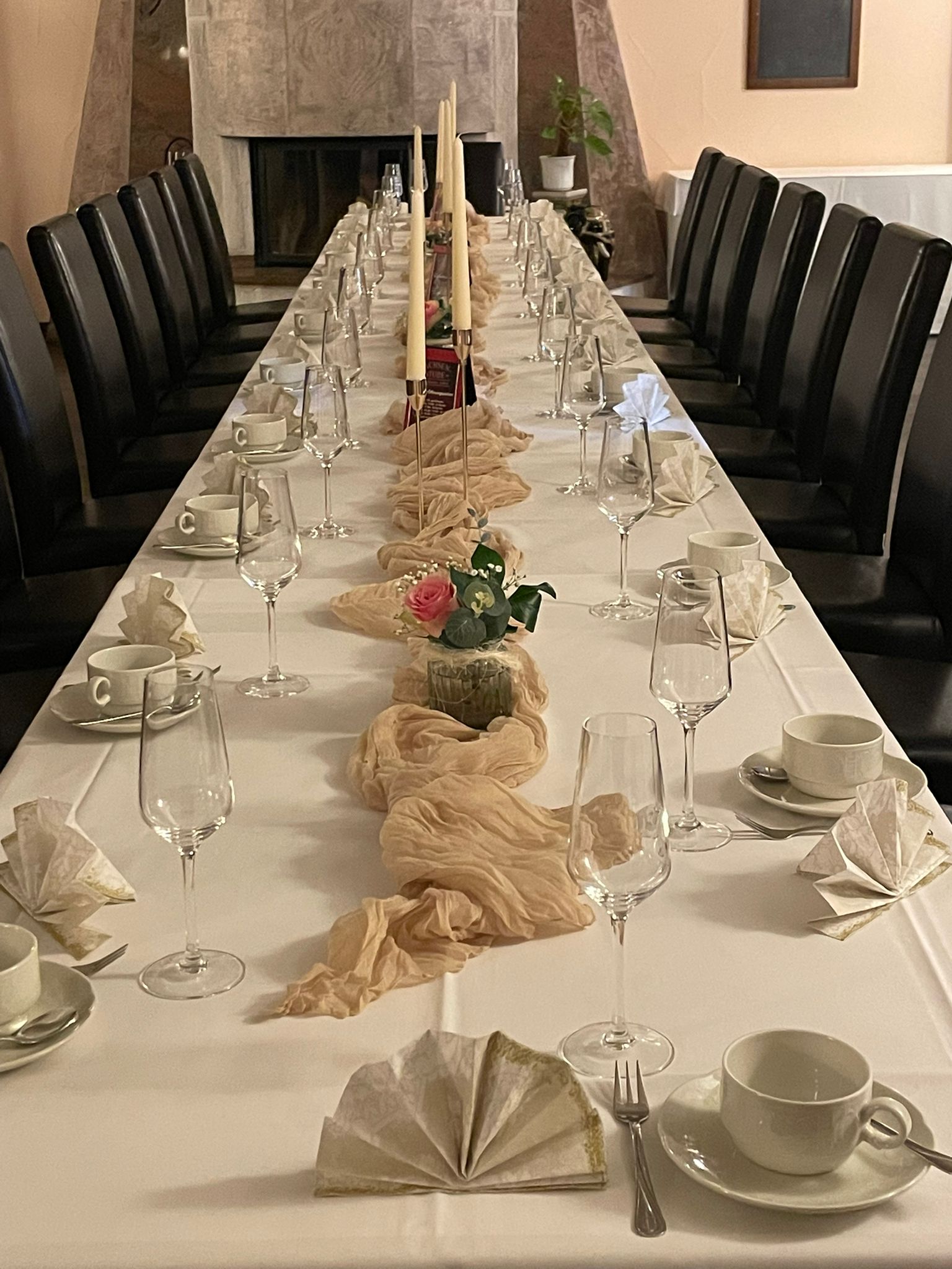 Festlich gedeckte Tafel mit Kerzen und Blumenschmuck am Kamin